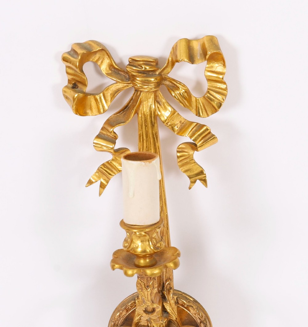 A pair of 19th-century French gilt bronze three-branch wall sconces styled with ribbon bow tops and tassel finials. View IV