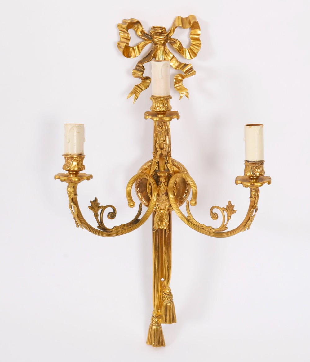 A pair of 19th-century French gilt bronze three-branch wall sconces styled with ribbon bow tops and tassel finials. View VII