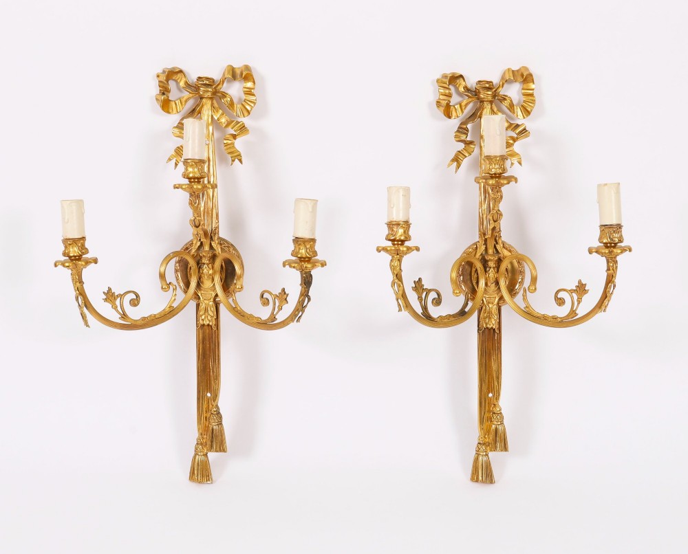 A pair of 19th-century French gilt bronze three-branch wall sconces styled with ribbon bow tops and tassel finials. View IX