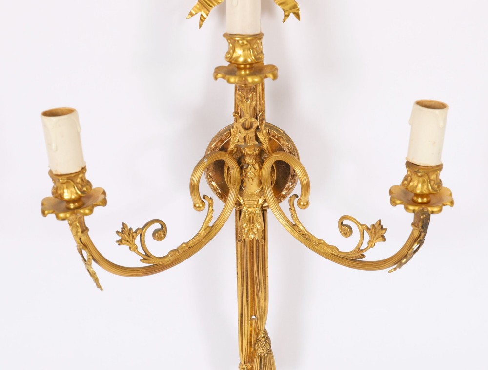 Set of four gilt bronze three-branch wall lights featuring ribbon bow cresting and hanging tassel drops. View V