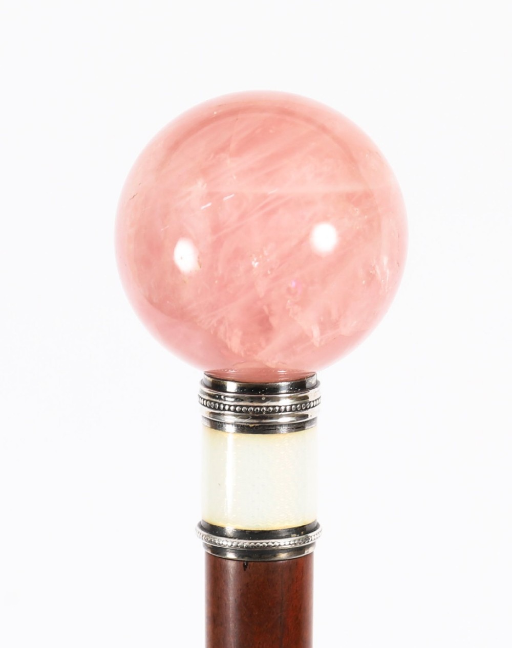 An antique walking stick featuring a spherical pink quartz pommel set above a white enamel collar with silver beaded borders and a dark wood shaft. View VII