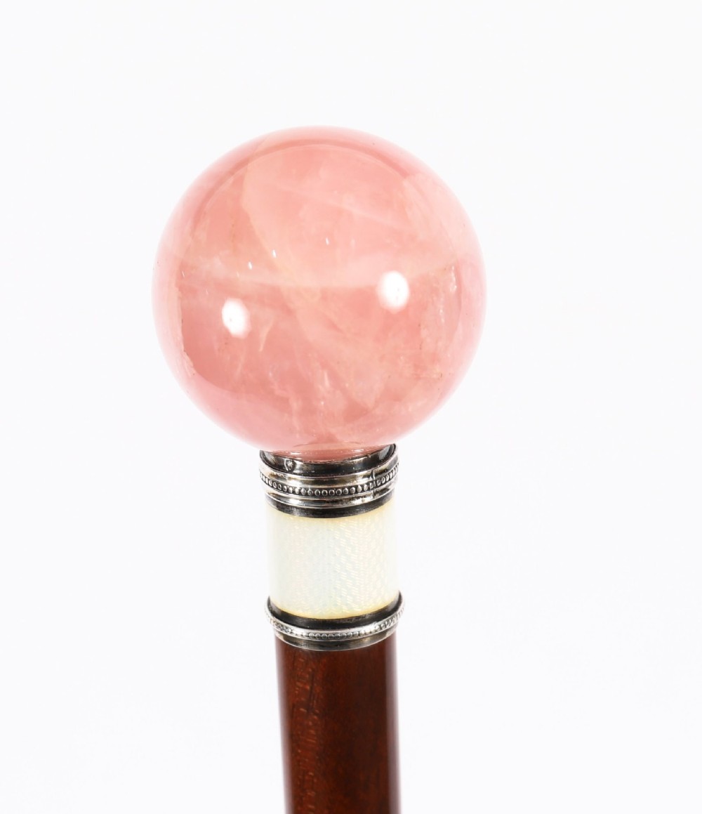 An antique walking stick featuring a spherical pink quartz pommel set above a white enamel collar with silver beaded borders and a dark wood shaft. View VIII