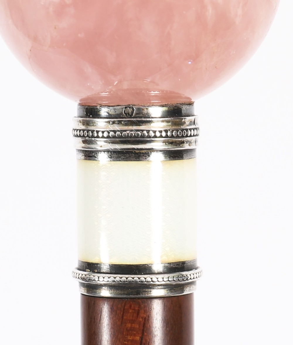 An antique walking stick featuring a spherical pink quartz pommel set above a white enamel collar with silver beaded borders and a dark wood shaft. View IX