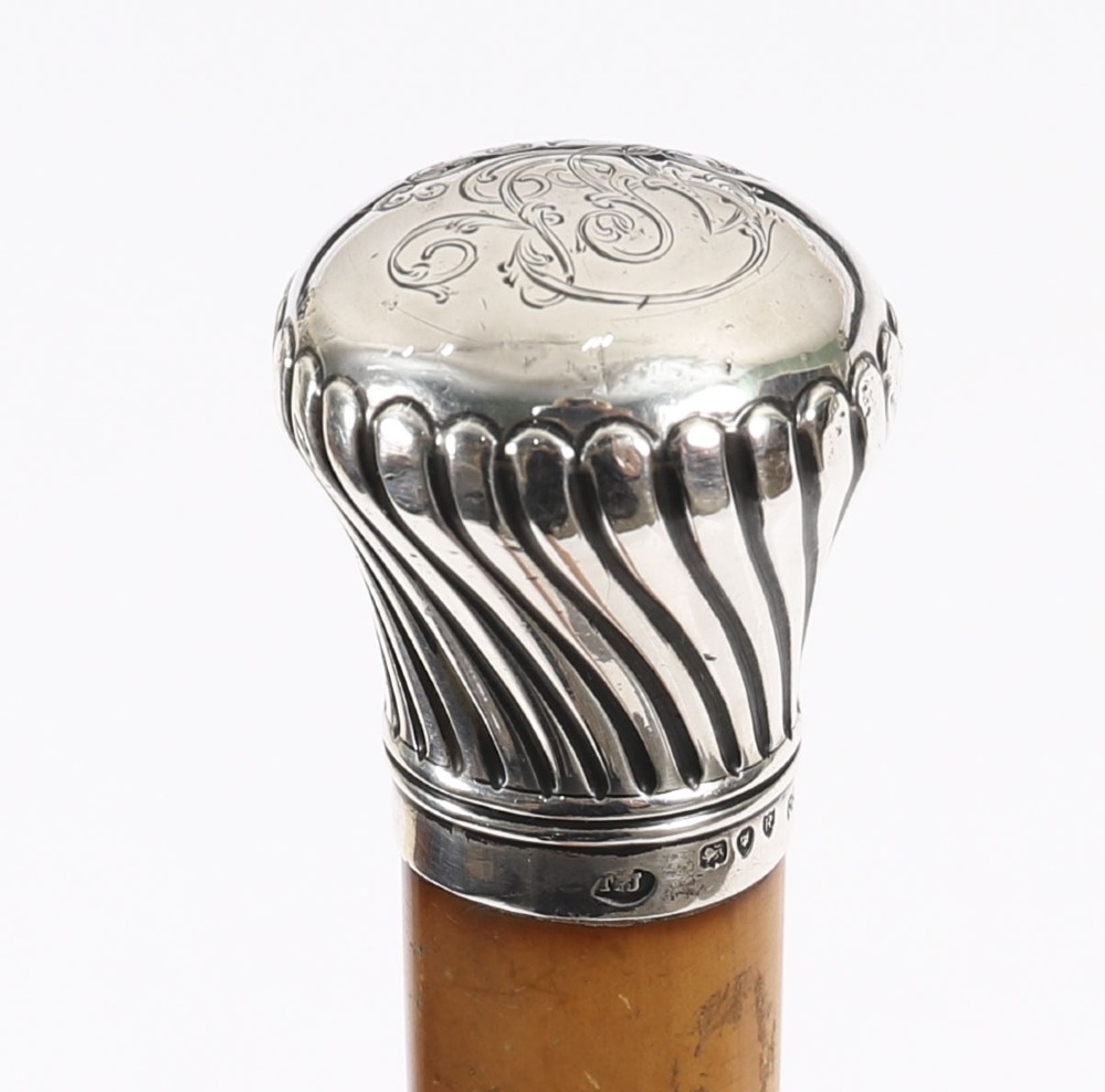Victorian walking cane featuring an engraved sterling silver pommel with spiralled fluting mounted on a light wood shaft. View VI