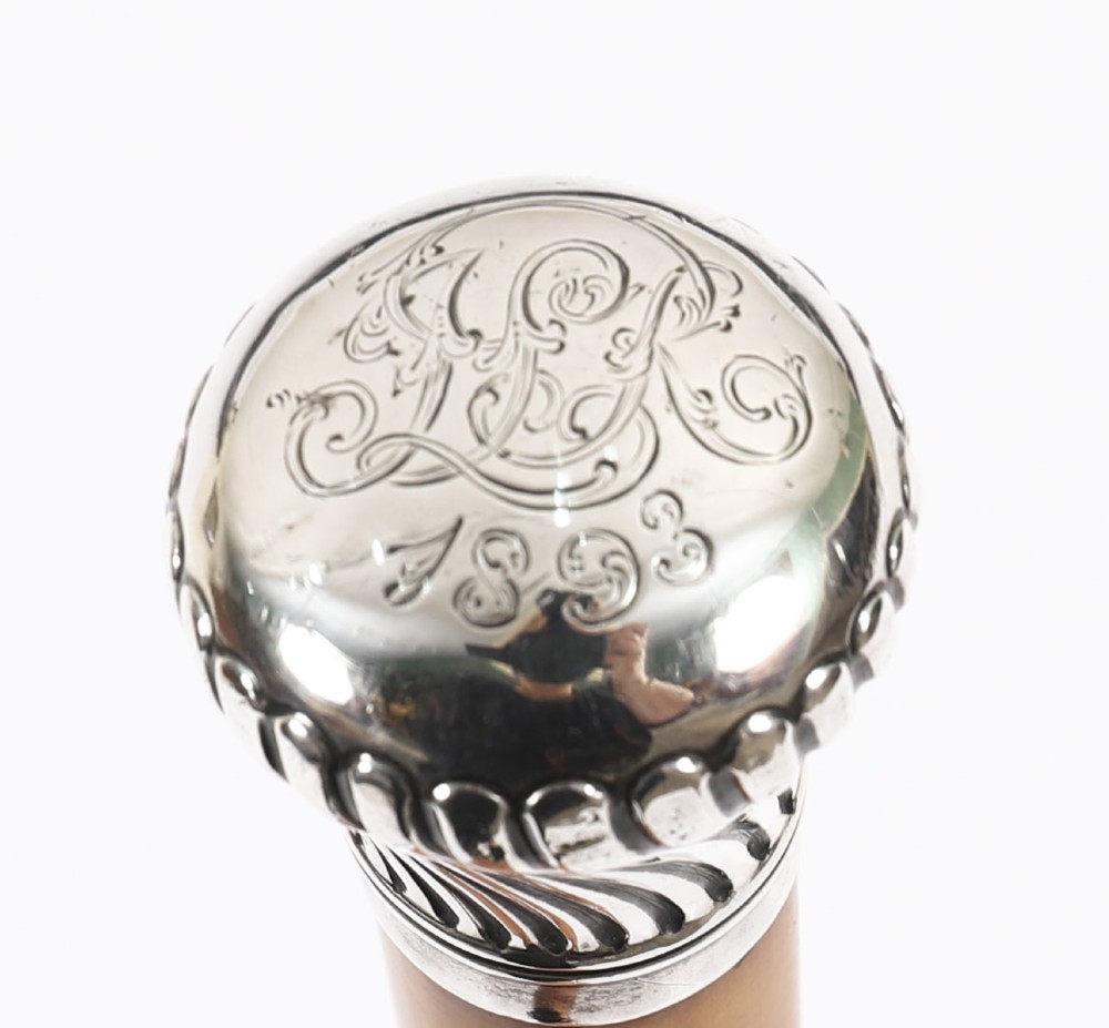 Victorian walking cane featuring an engraved sterling silver pommel with spiralled fluting mounted on a light wood shaft. View VII