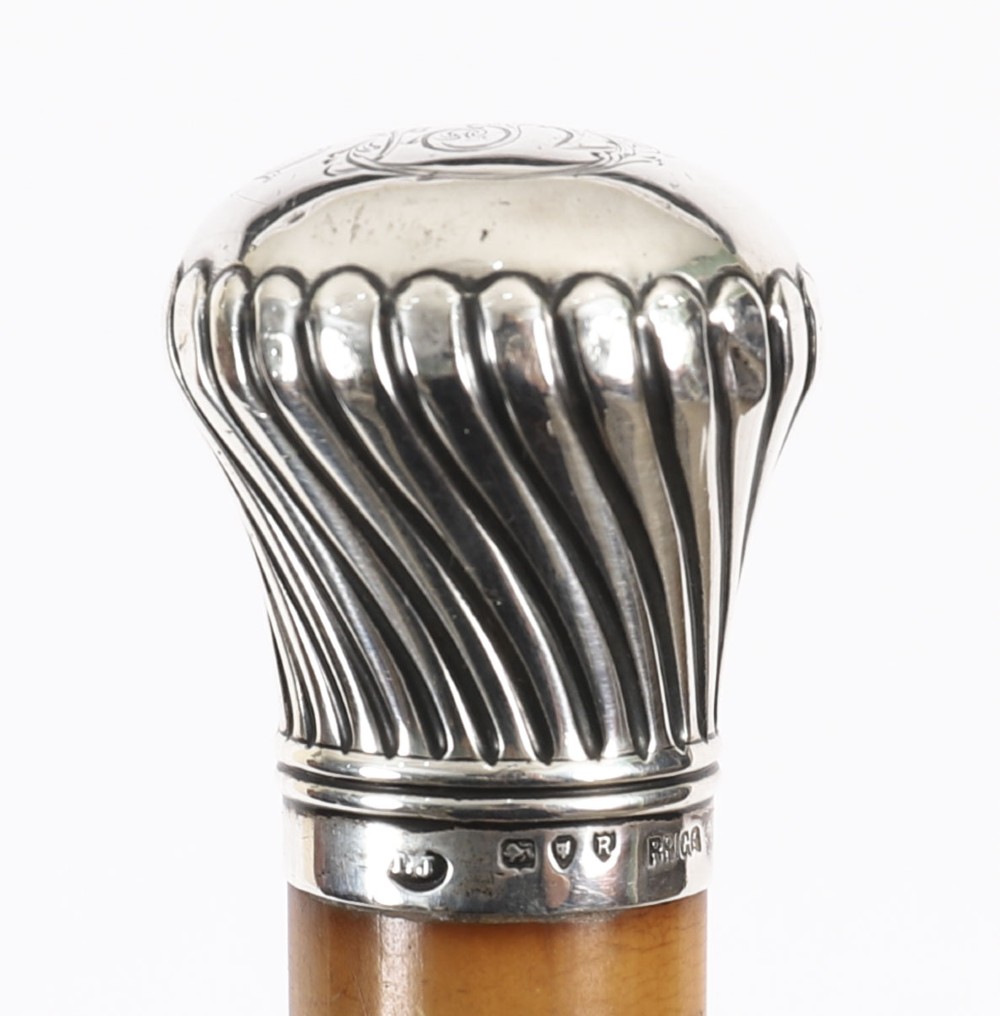 Victorian walking cane featuring an engraved sterling silver pommel with spiralled fluting mounted on a light wood shaft. View X