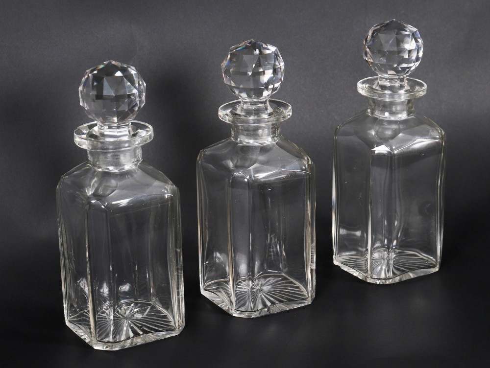An open and closed 19th-century Victorian burr walnut tantalus box containing three cut crystal decanters, brass-mounted liqueur glasses, and a deep blue velvet lining. View X