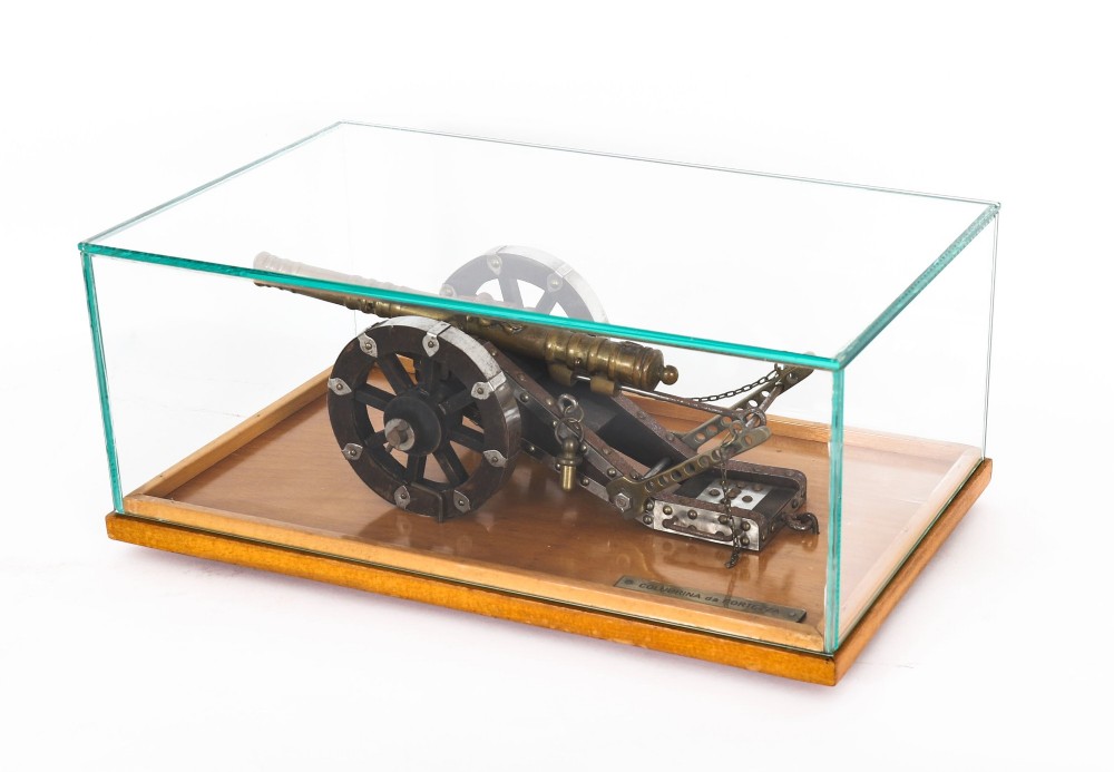 A 19th-century bronze model cannon mounted on a dark wooden carriage and enclosed within a clear glass display case. View VII