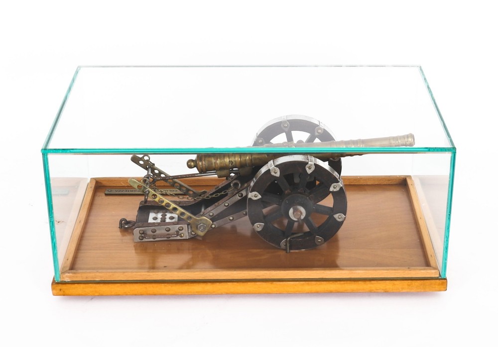 A 19th-century bronze model cannon mounted on a dark wooden carriage and enclosed within a clear glass display case. View XIII