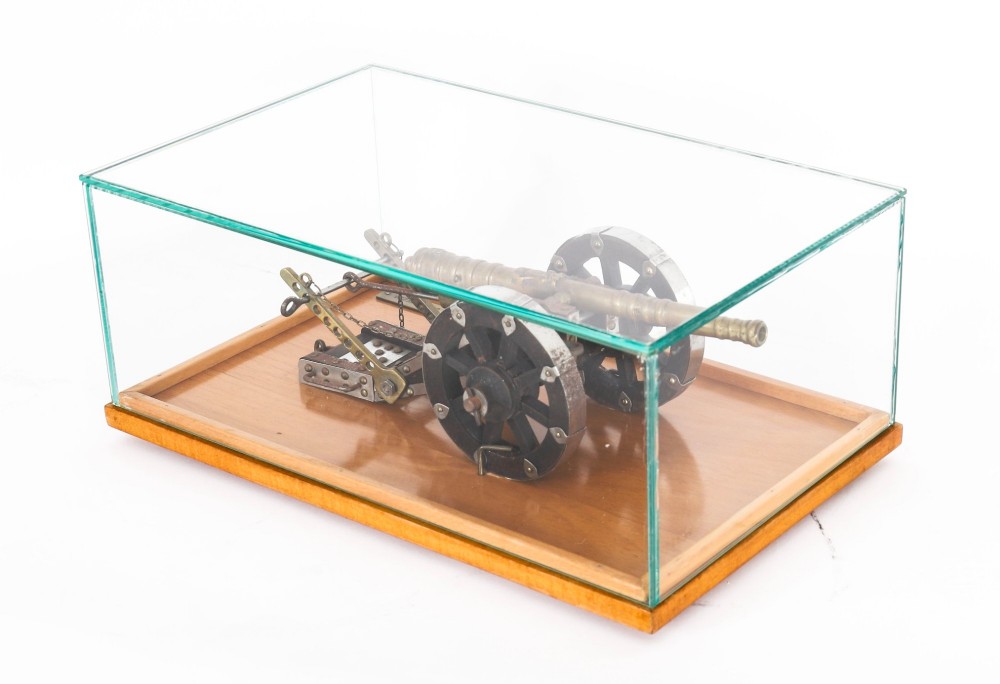 A 19th-century bronze model cannon mounted on a dark wooden carriage and enclosed within a clear glass display case. View XV