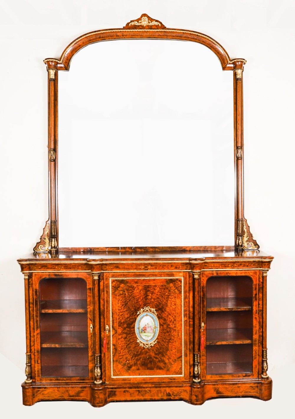 A nineteenth-century Victorian burr walnut credenza featuring an arched mirror back, glazed side doors, and a central cupboard inlaid with a porcelain plaque.
