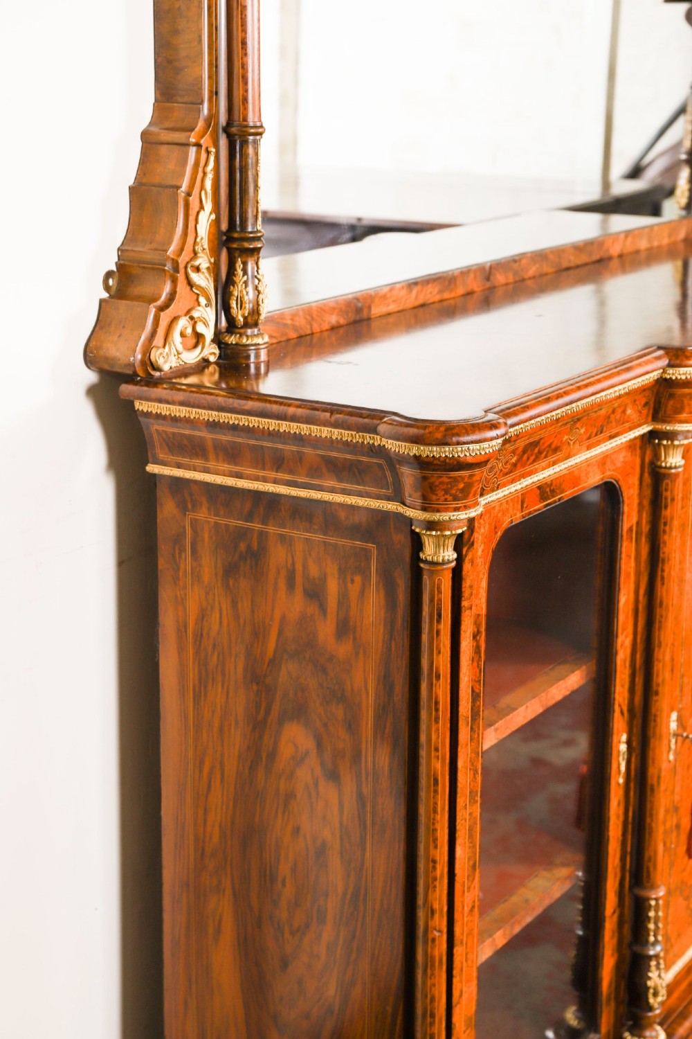 A nineteenth-century Victorian burr walnut credenza featuring an arched mirror back, glazed side doors, and a central cupboard inlaid with a porcelain plaque. View X