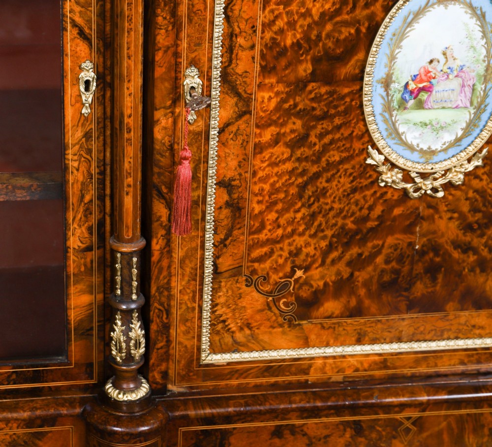 A nineteenth-century Victorian burr walnut credenza featuring an arched mirror back, glazed side doors, and a central cupboard inlaid with a porcelain plaque. View XI
