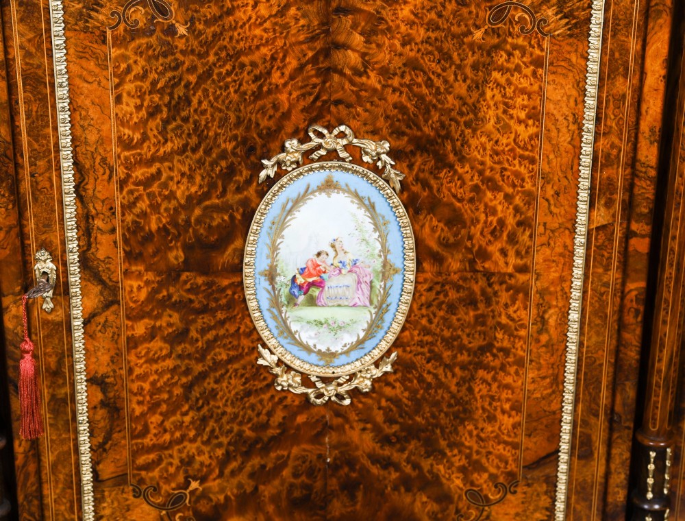 A nineteenth-century Victorian burr walnut credenza featuring an arched mirror back, glazed side doors, and a central cupboard inlaid with a porcelain plaque. View XII