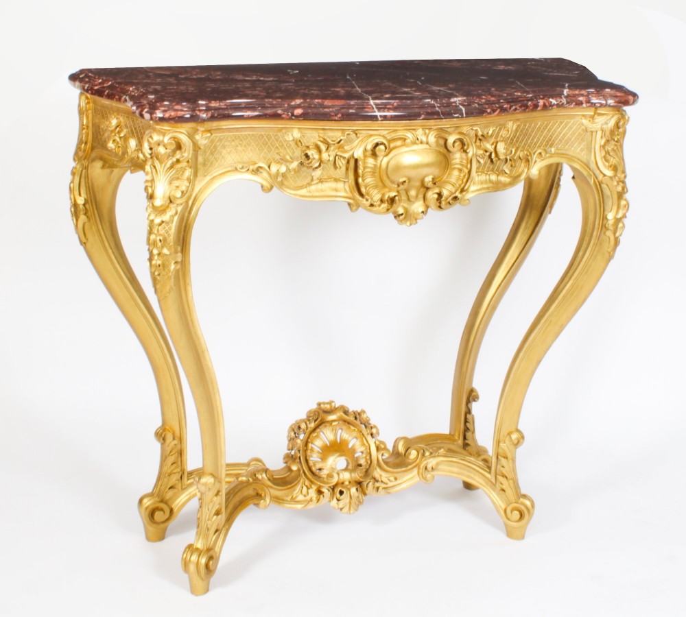 A 19th-century French Louis XV Revival giltwood console table featuring carved cabriole legs, a central shell cartouche stretcher, and a reddish-brown marble top.