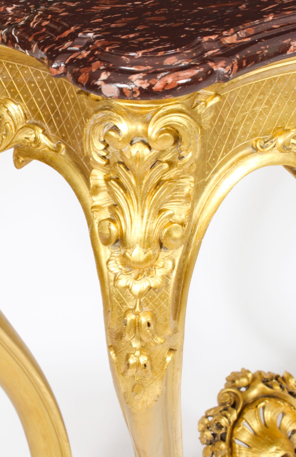 A 19th-century French Louis XV Revival giltwood console table featuring carved cabriole legs, a central shell cartouche stretcher, and a reddish-brown marble top. View IX