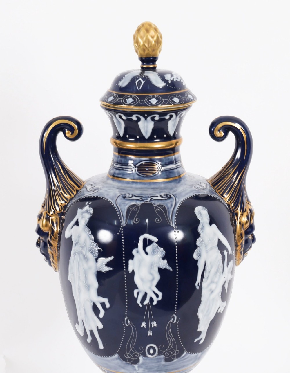 A pair of cobalt blue and white porcelain lidded vases featuring classical figures, scrolling handles, and gilded finials. View V