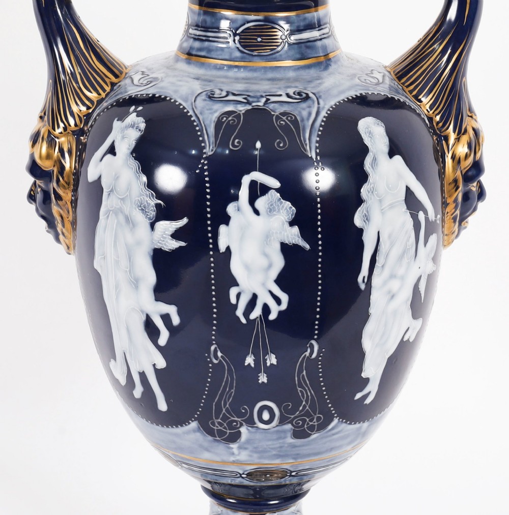 A pair of cobalt blue and white porcelain lidded vases featuring classical figures, scrolling handles, and gilded finials. View VI