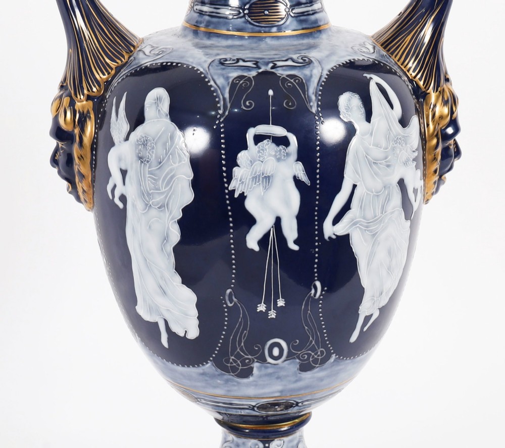 A pair of cobalt blue and white porcelain lidded vases featuring classical figures, scrolling handles, and gilded finials. View IX