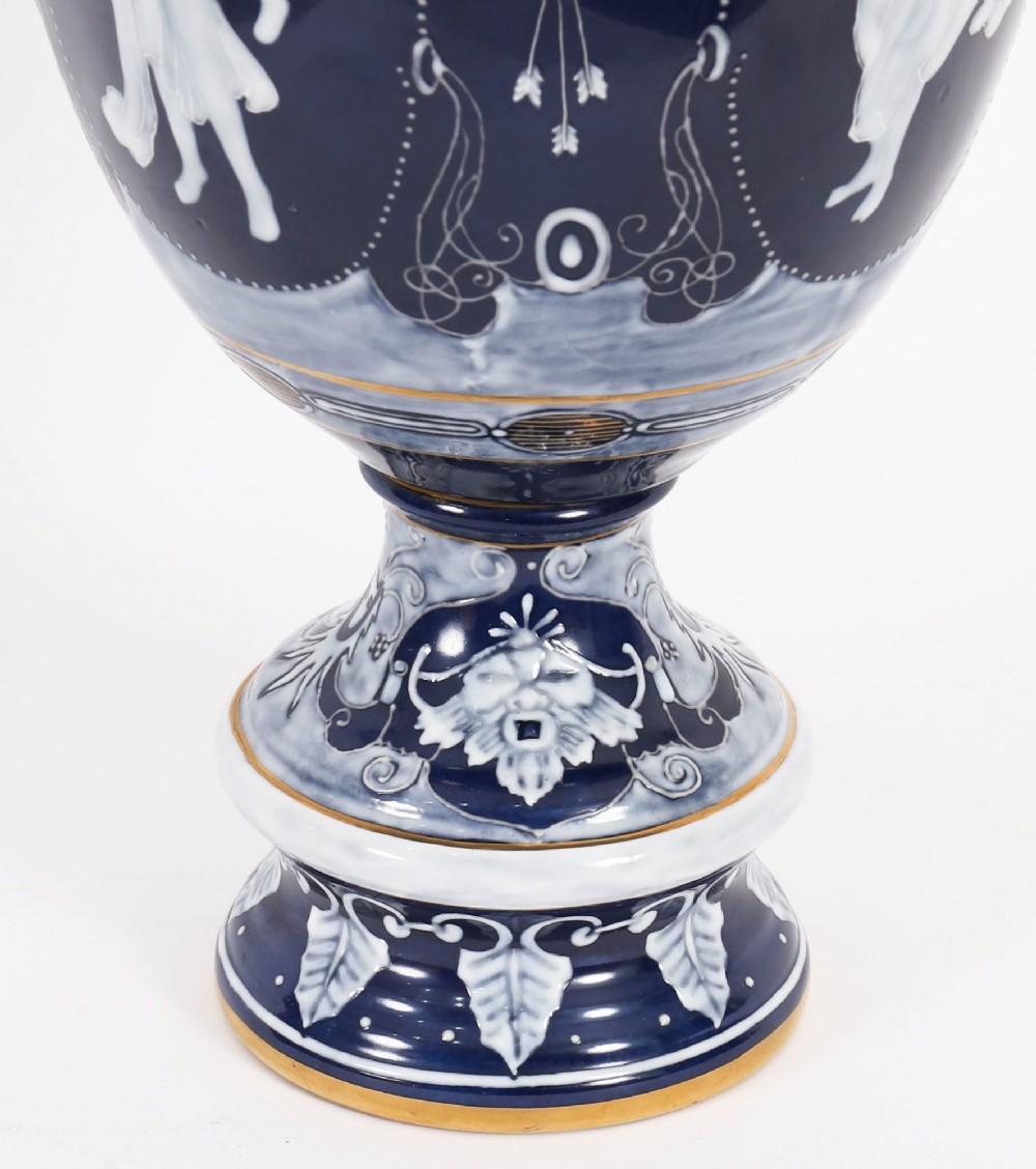 A pair of cobalt blue and white porcelain lidded vases featuring classical figures, scrolling handles, and gilded finials. View XIV