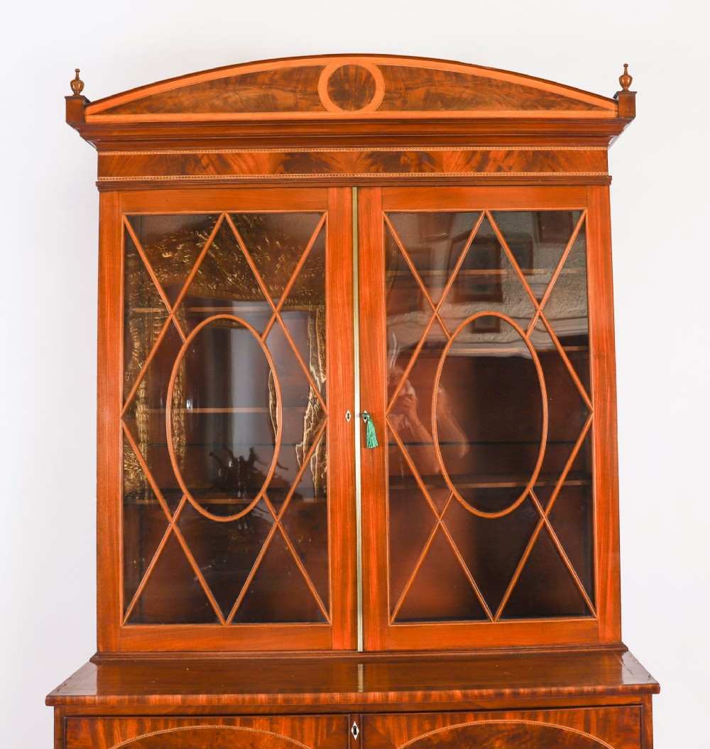 An antique George III flame mahogany secretaire bookcase featuring a shaped pediment, two upper astragal glazed doors, and a lower four-drawer chest base with brass ring handles. View IV