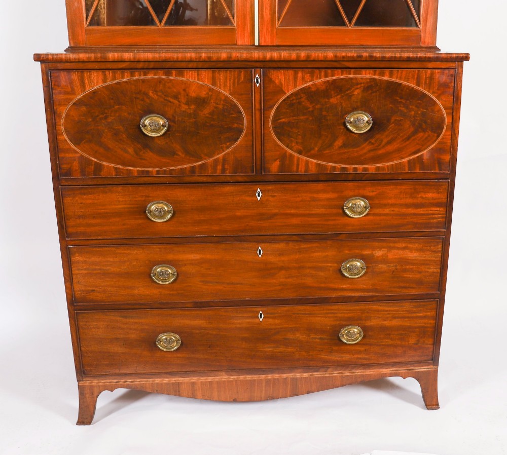 An antique George III flame mahogany secretaire bookcase featuring a shaped pediment, two upper astragal glazed doors, and a lower four-drawer chest base with brass ring handles. View VI