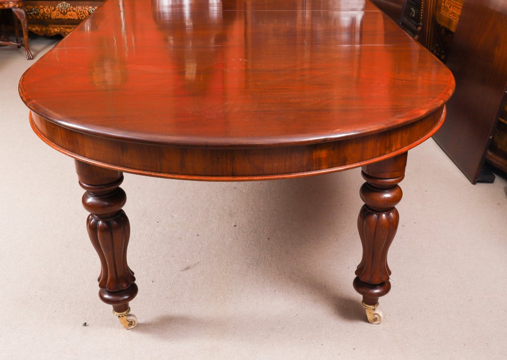 A large George III extending dining table in Cuban flame mahogany with turned fluted legs and brass castors. View XV