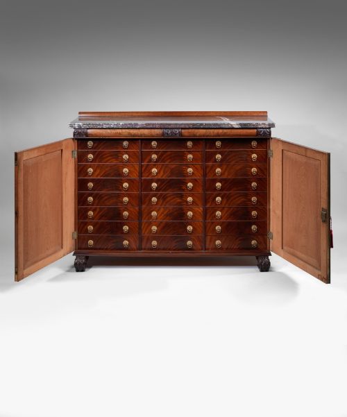 fig 1. A Regency flame mahogany cabinet featuring a grey veined marble top, double panelled doors, and carved acanthus leaf pilasters.