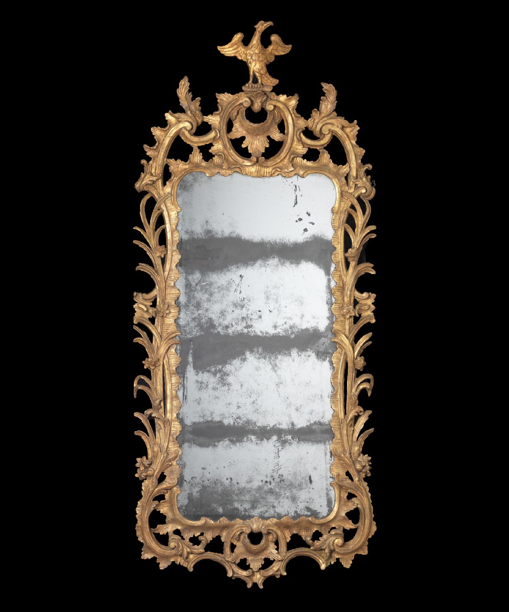 An 18th-century Chippendale period giltwood wall mirror featuring an intricately carved Rococo scrollwork frame topped with a carved phoenix crest.