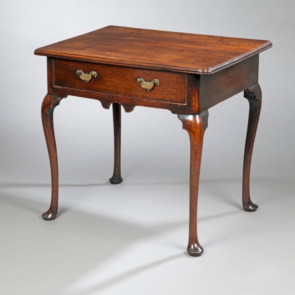 A George II mahogany side table with cabriole legs, pad feet, a moulded top, and a single frieze drawer fitted with brass handles.