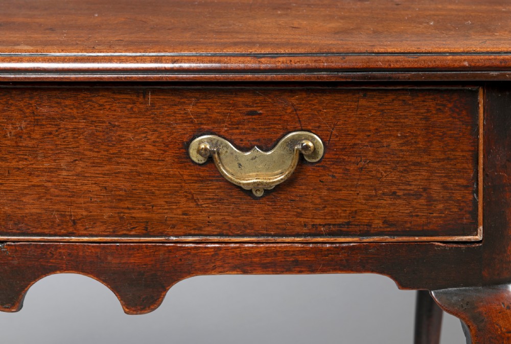 A George II mahogany side table with cabriole legs, pad feet, a moulded top, and a single frieze drawer fitted with brass handles. View IV