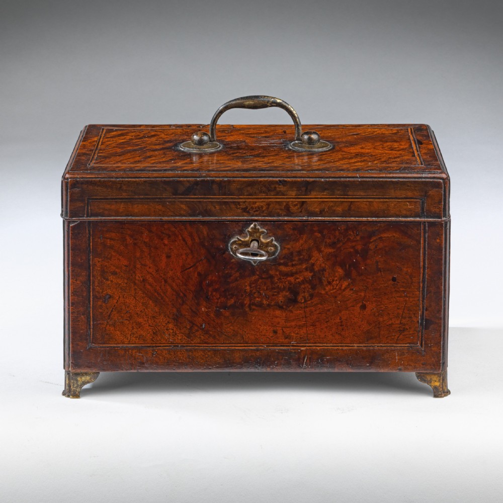 A rectangular George II burr walnut tea caddy with a top brass carrying handle, crossbanded inlay borders, and a decorative brass escutcheon with key.