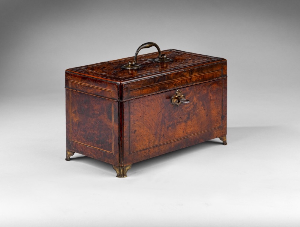 A rectangular George II burr walnut tea caddy with a top brass carrying handle, crossbanded inlay borders, and a decorative brass escutcheon with key. View II