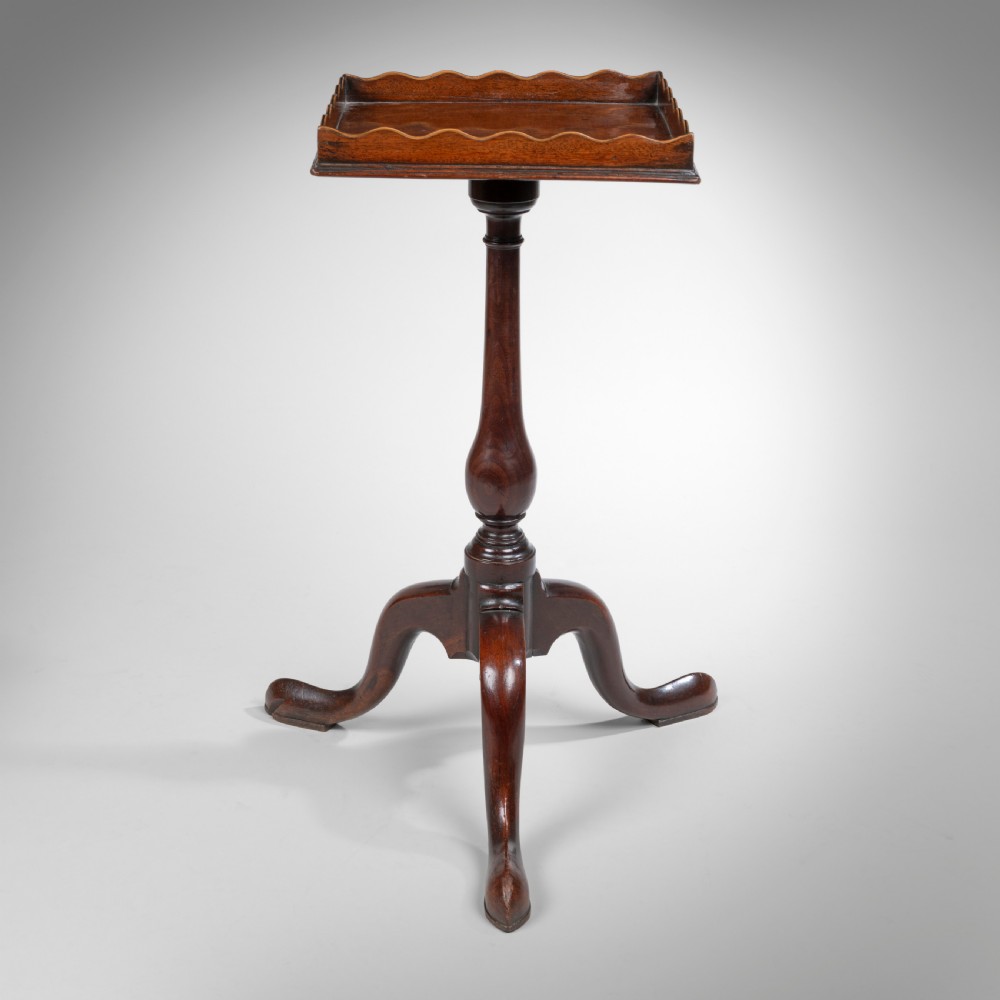 An 18th-century Georgian mahogany kettle stand featuring a scalloped gallery top, turned baluster stem, and tripod cabriole legs.