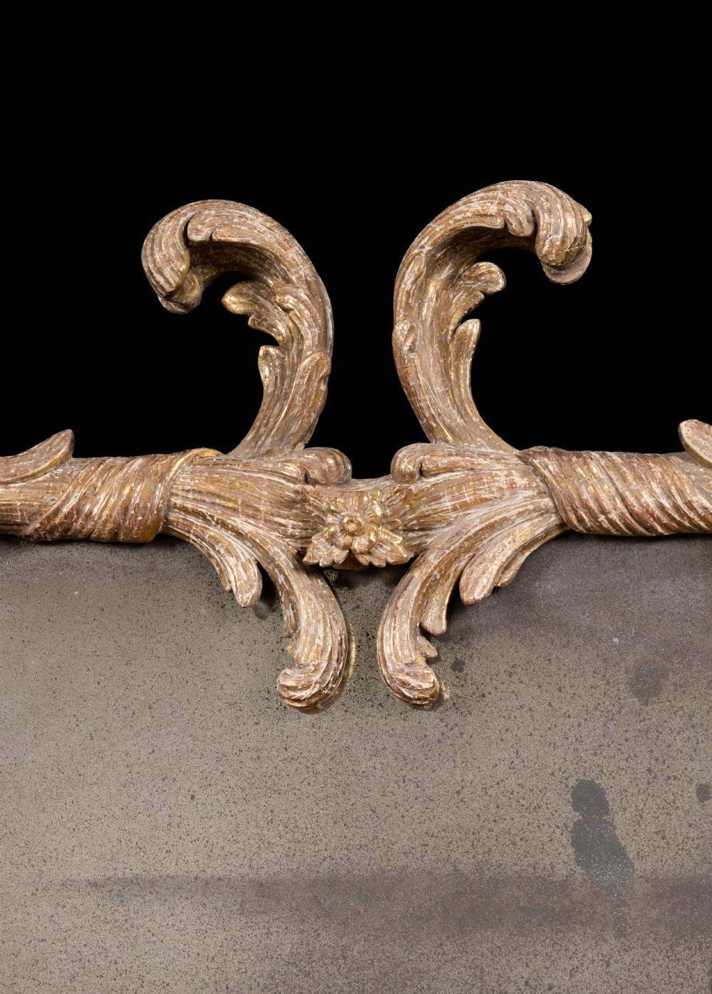 A matching pair of horizontal oval Georgian giltwood mirrors featuring carved leafy scrollwork frames and aged glass. View III
