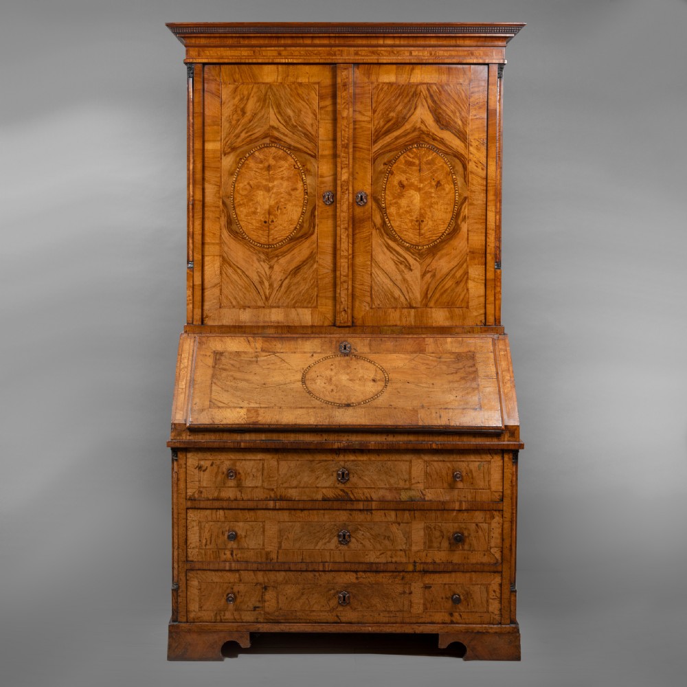 An eighteenth-century walnut bureau bookcase with double panelled doors above a sloping slant-front writing surface and drawers.