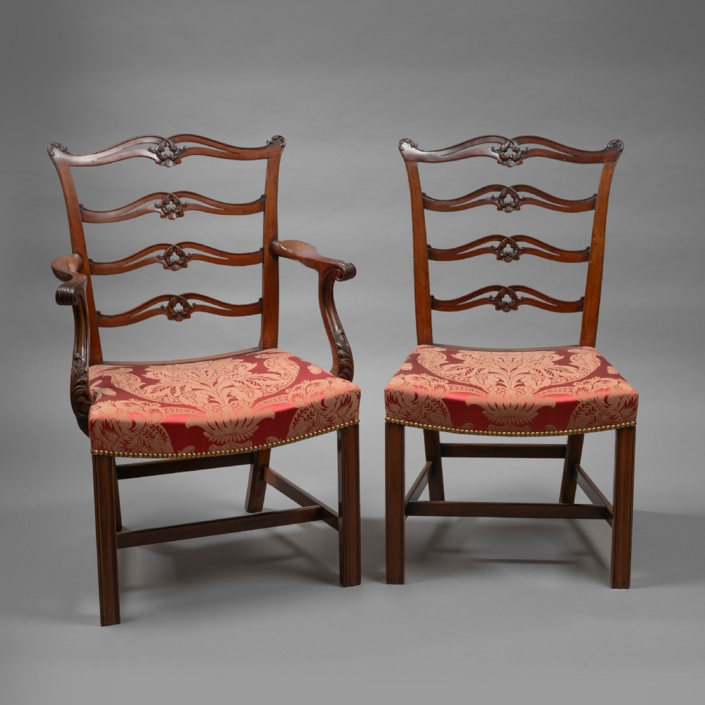 A set of Georgian mahogany ladder-back dining chairs including a carver armchair with red patterned damask upholstery.