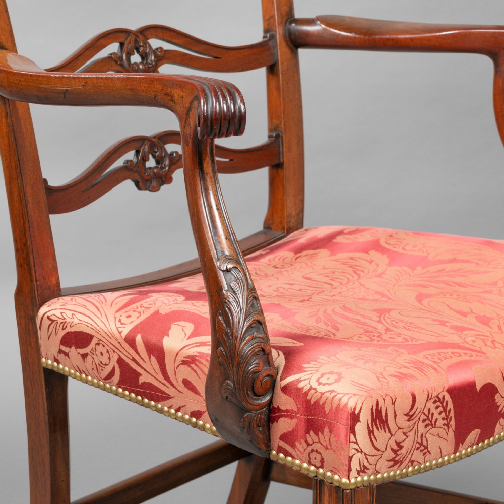 A set of Georgian mahogany ladder-back dining chairs including a carver armchair with red patterned damask upholstery. View V