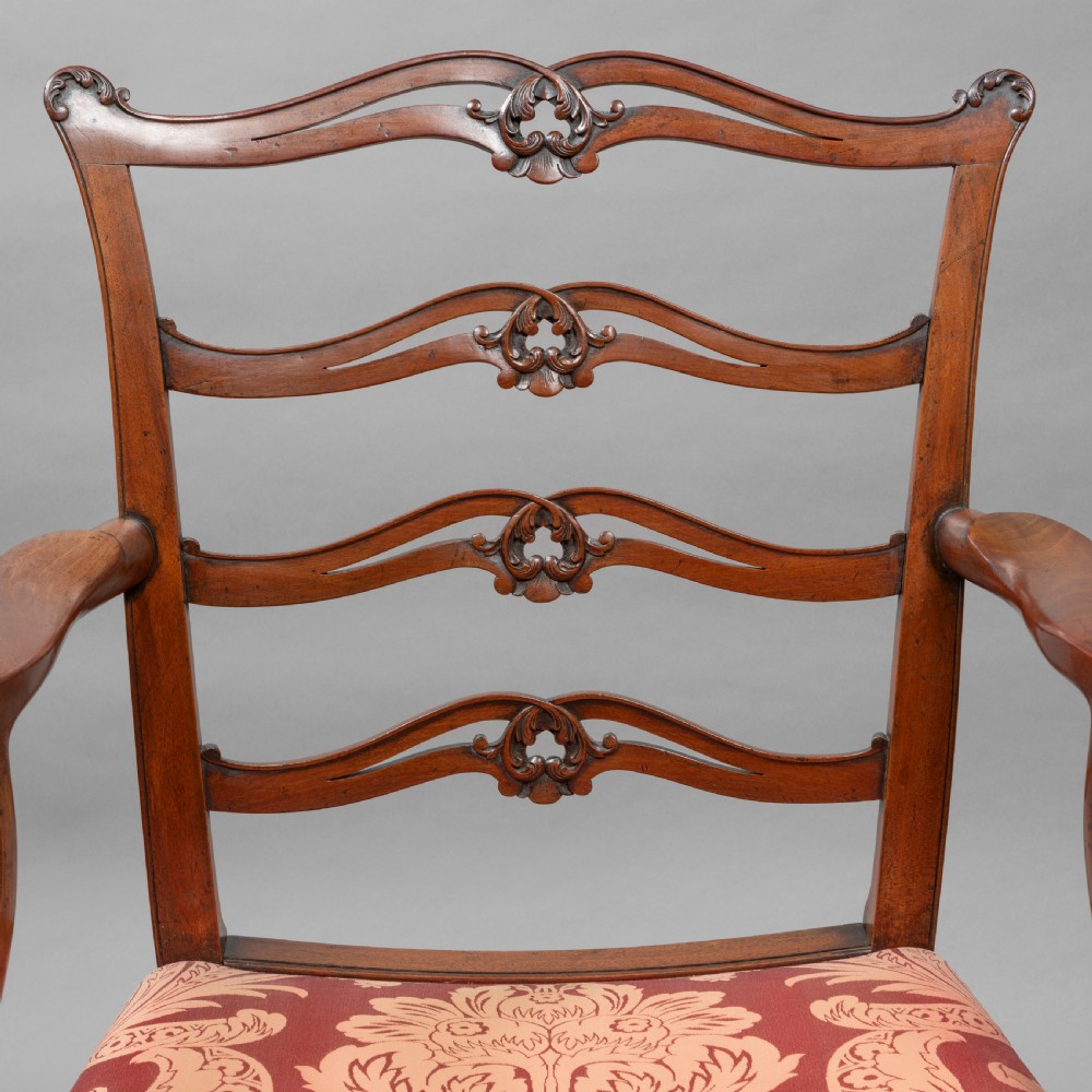 A set of Georgian mahogany ladder-back dining chairs including a carver armchair with red patterned damask upholstery. View VI