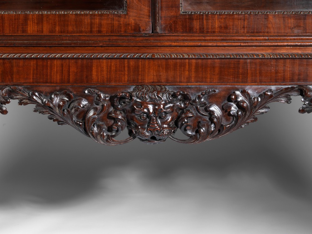 A dark mahogany George II style display cabinet on stand featuring glazed double doors, a carved apron with central mask detail, and cabriole legs with claw and ball feet. View IV
