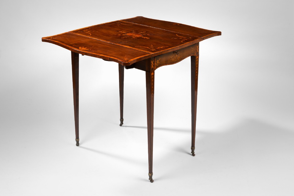 A Sheraton harewood pembroke table featuring floral marquetry inlay on the top and leaves, supported by slender square tapered legs with brass castors. View VI