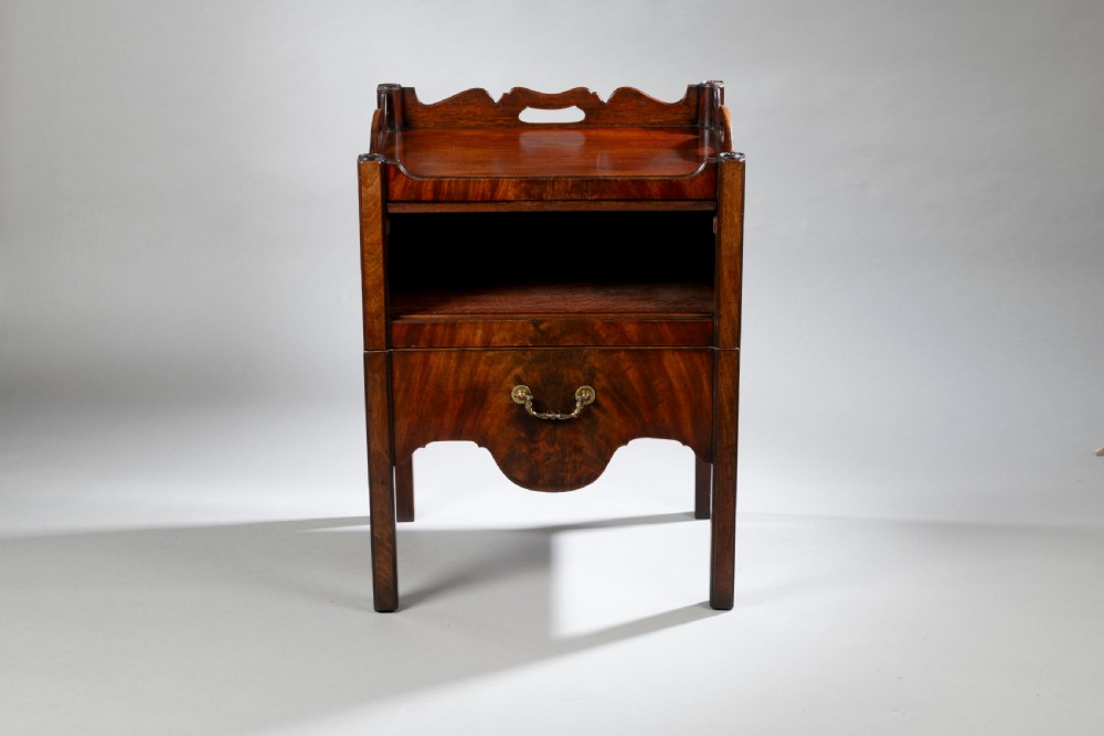 A pair of Georgian Chippendale mahogany tray top commodes featuring pierced side handles, galleried rims, flame mahogany fronts, and brass handles on square legs. View IV