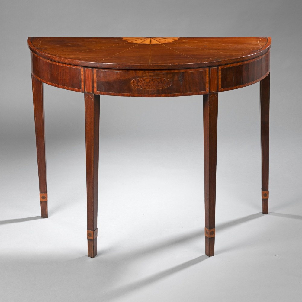 A Georgian mahogany demi-lune console table featuring fan marquetry inlay and tapered square legs.