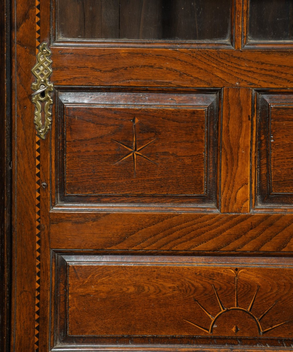 An 18th-century Georgian dark oak corner cupboard featuring a swan-neck pediment, glazed upper door panels, and decorative inlay motifs. View IV