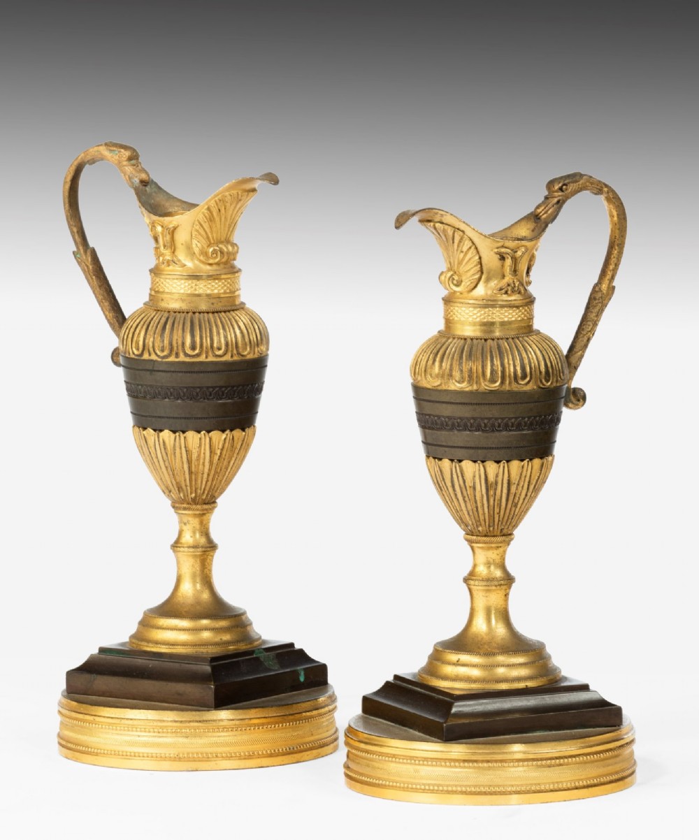 A pair of 19th-century Neoclassical ewers featuring reeded gilt-bronze urn bodies with dark patinated bronze central bands, cast handles, and tiered bases. View III
