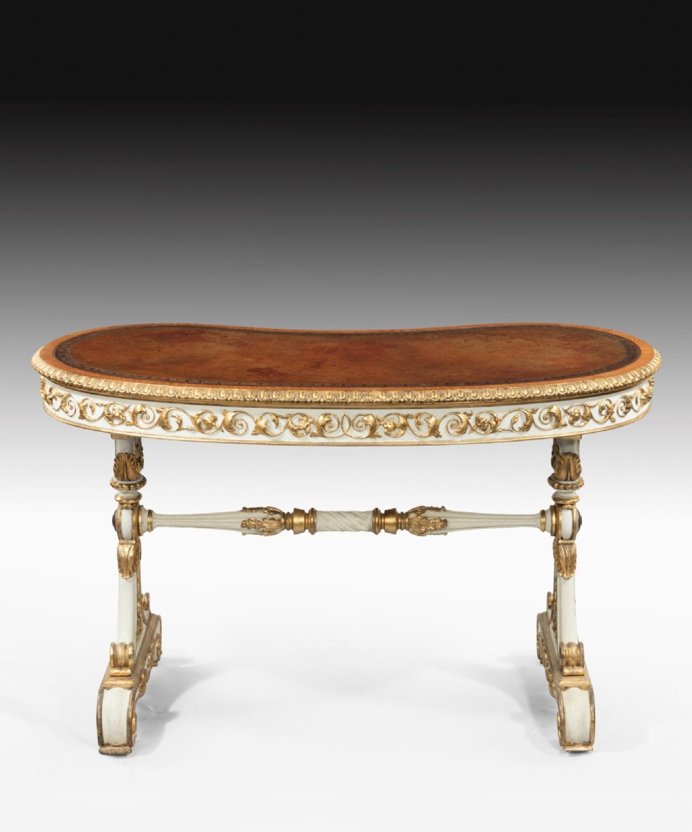 A kidney-shaped William IV writing table featuring an ivory-painted finish, detailed carved giltwood embellishments, a turned stretcher, and a brown leather inset surface. View II