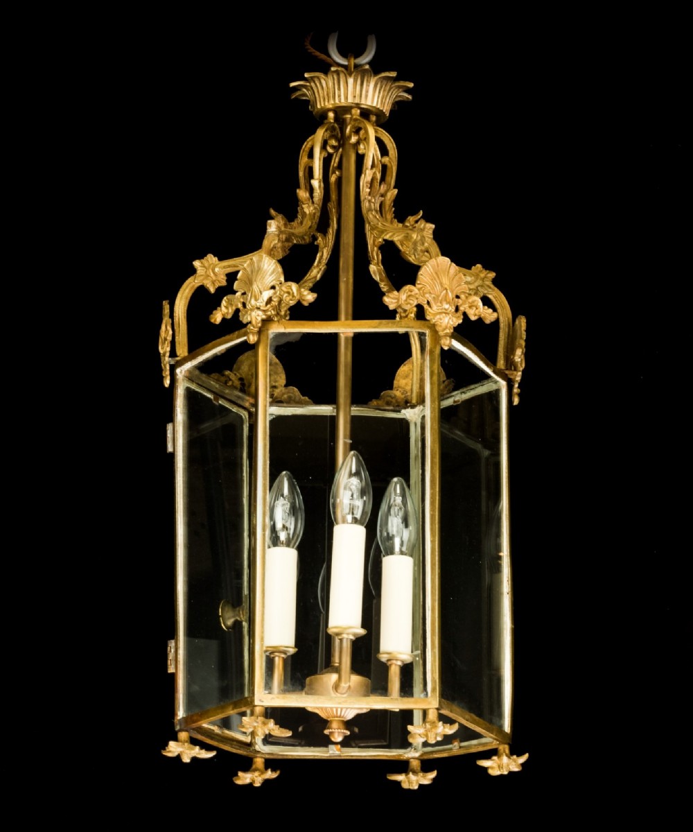 An antique Neo-Classical brass hanging hall lantern featuring glazed glass panels and three internal candle-style lights. View II