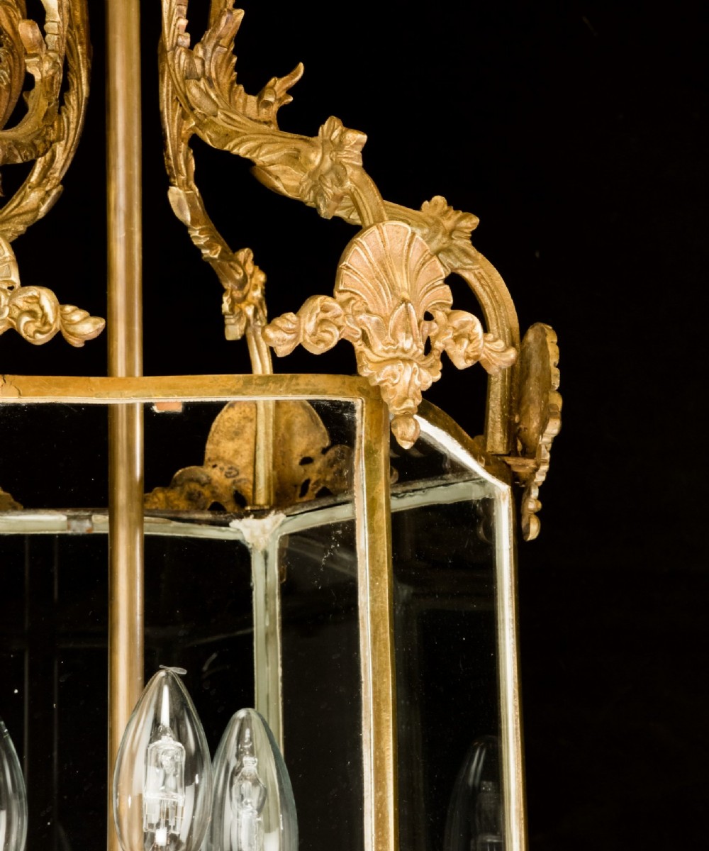 An antique Neo-Classical brass hanging hall lantern featuring glazed glass panels and three internal candle-style lights. View IV