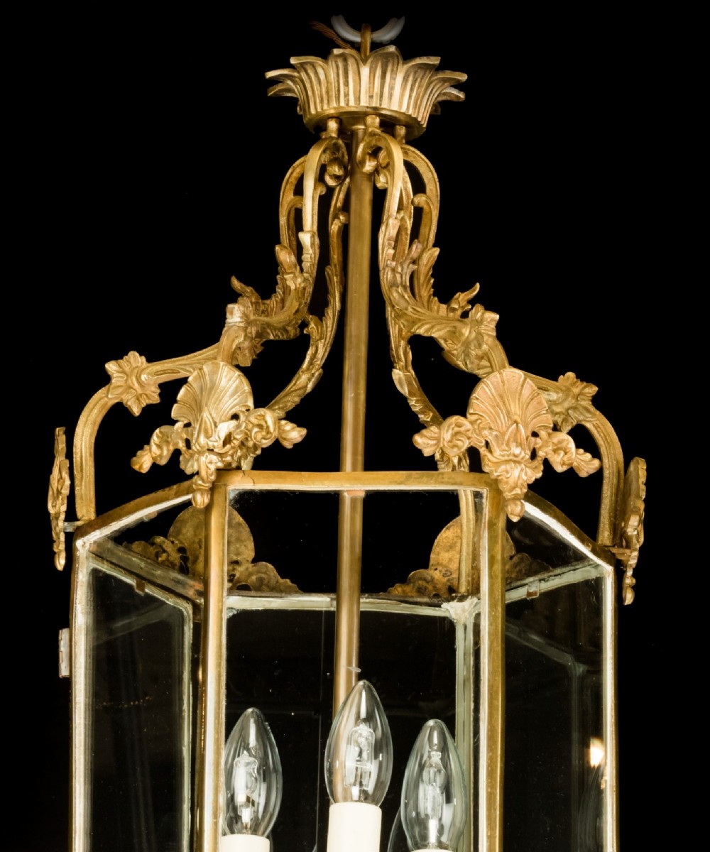 An antique Neo-Classical brass hanging hall lantern featuring glazed glass panels and three internal candle-style lights. View V