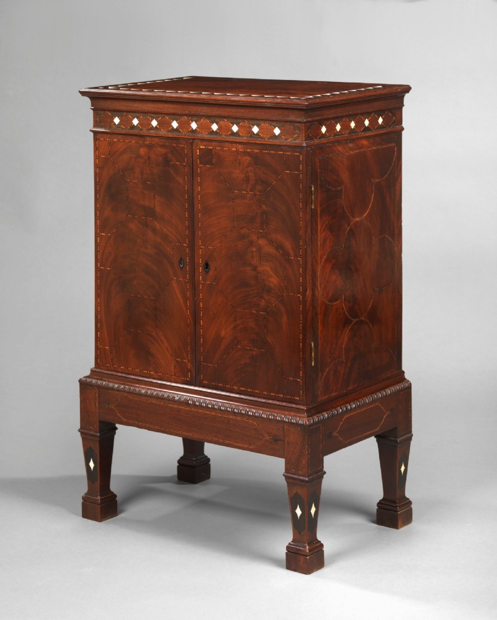 An 18th-century Chippendale mahogany cabinet on stand featuring geometric bone inlay details, two panelled doors, and square legs. View II